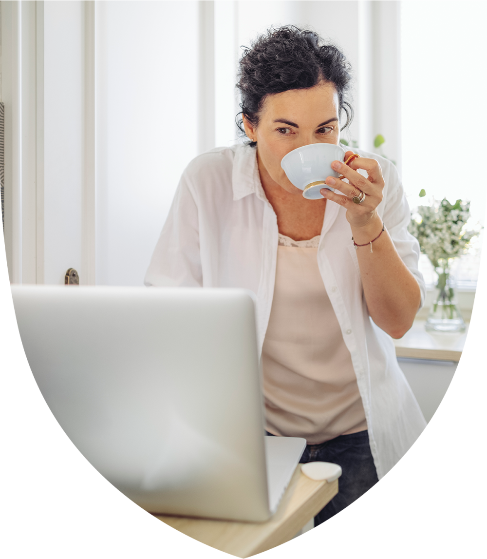 Woman drinking tea at a laptop