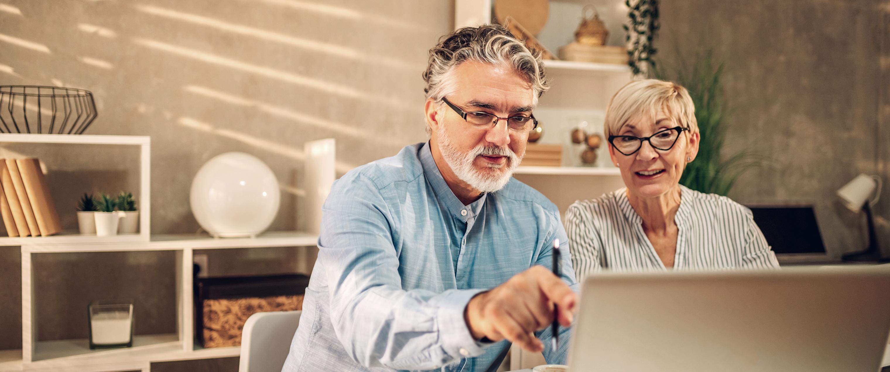 Elderly couple discussing finances while looking at computer together