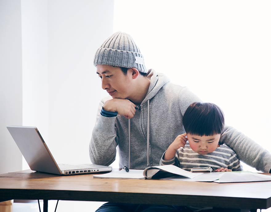 Man working at a laptop with his child