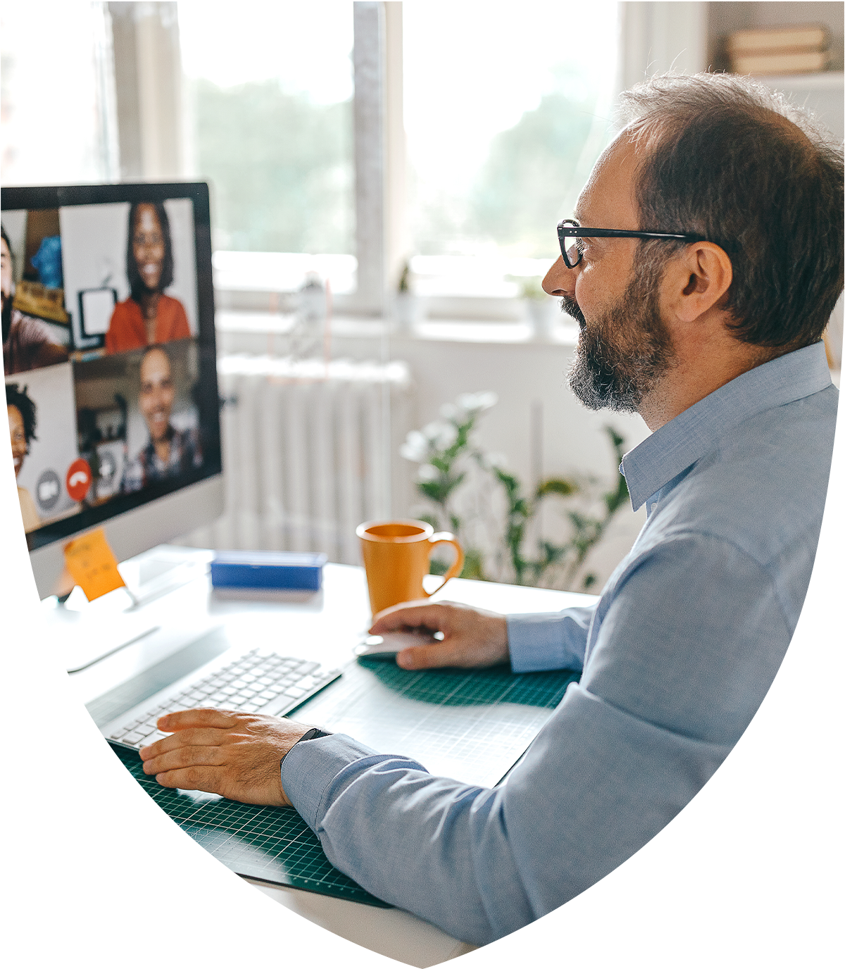 Man looking at a computer showing other people on the screen having a meeting