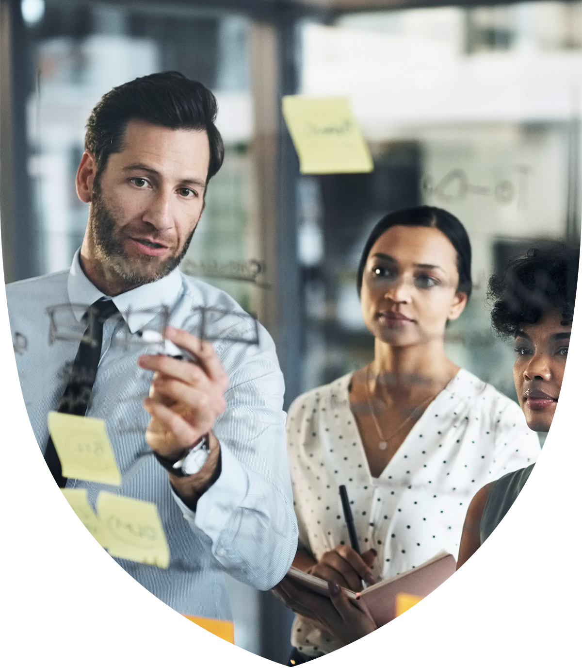 Three people looking at a glass whiteboard