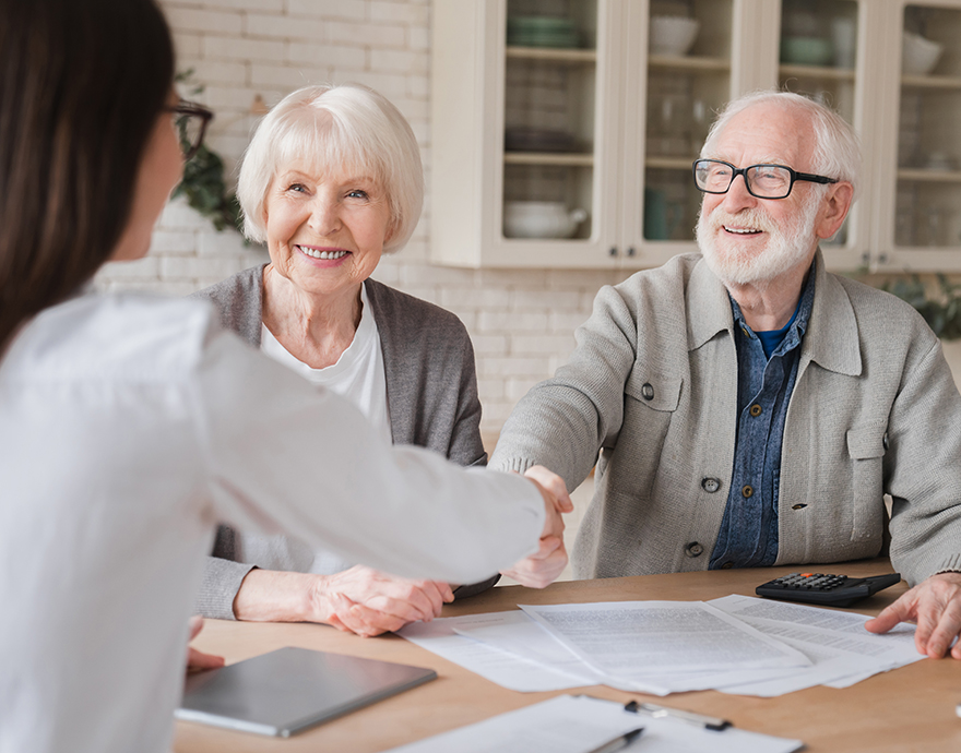 An elderly couple talking to a woman across a table