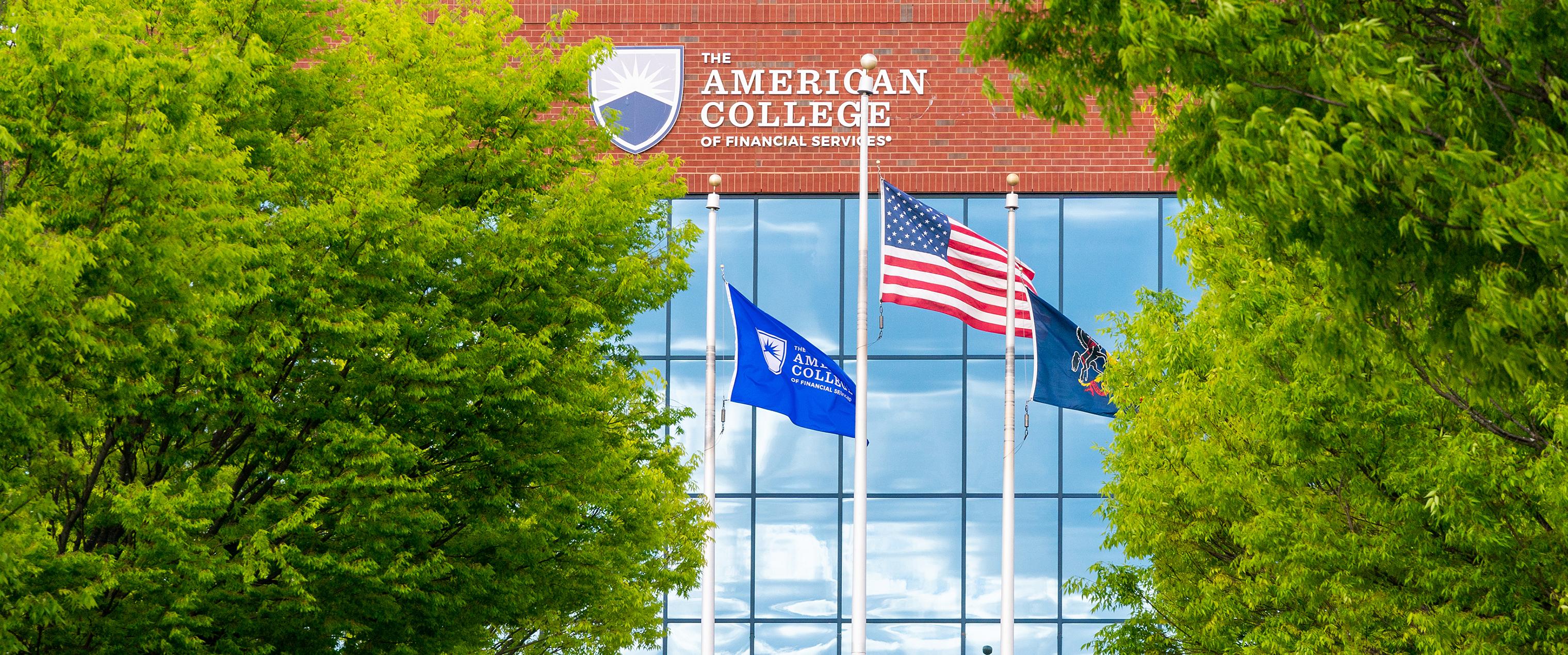 The American flag and college flag outside of the college headquarters 