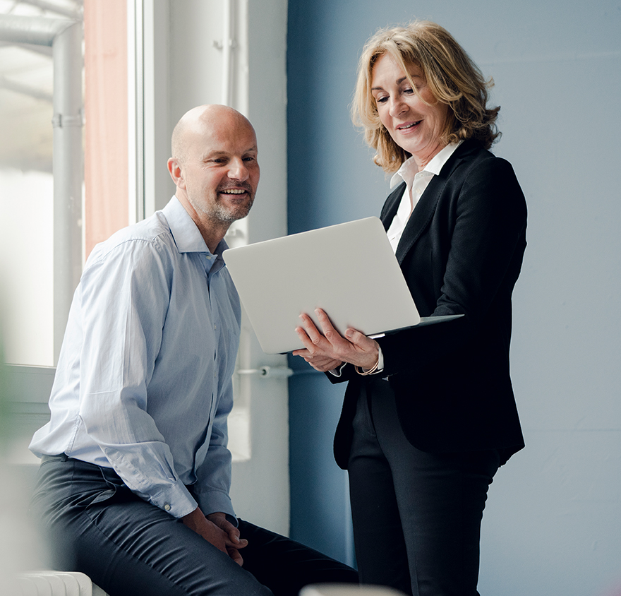 A woman and a man talking and looking at a laptop