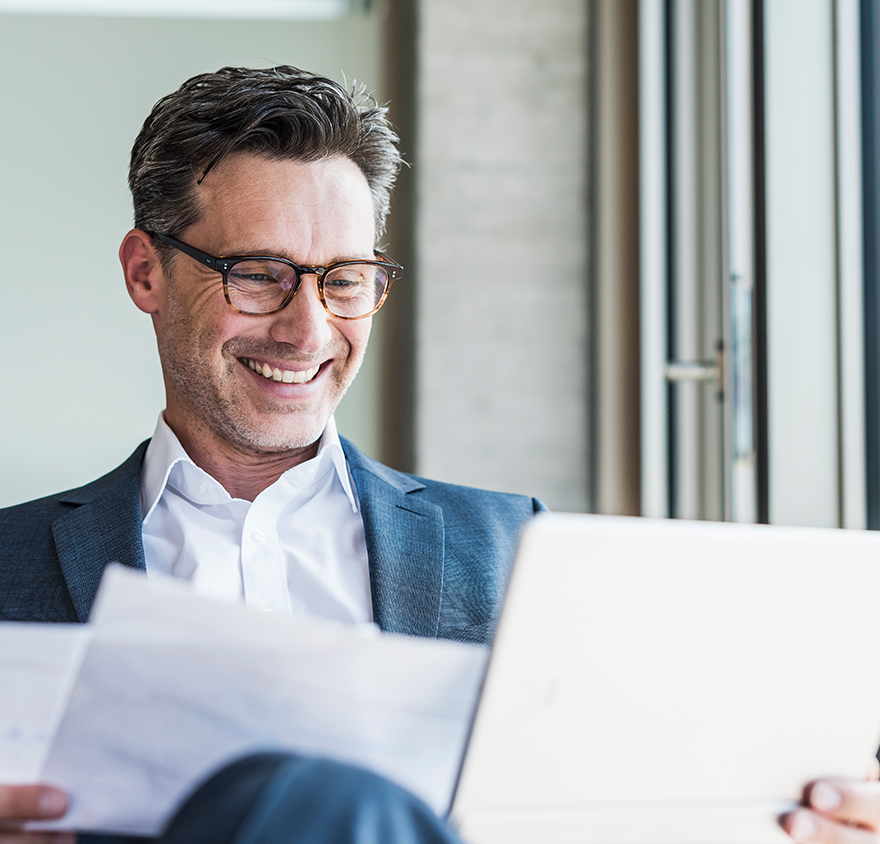 A man looking at a tablet and piece of paper