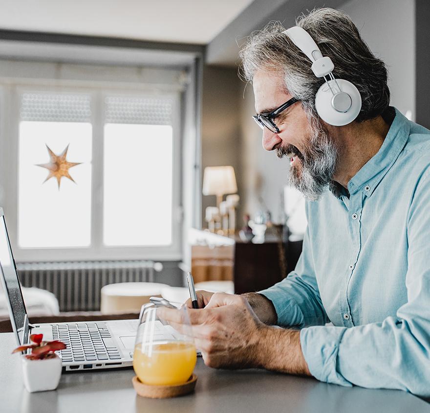 Image of a man at a laptop wearing headphones