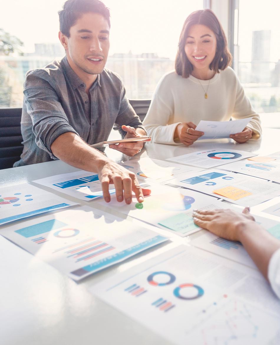 Three people meeting and pointing to graphs on the table