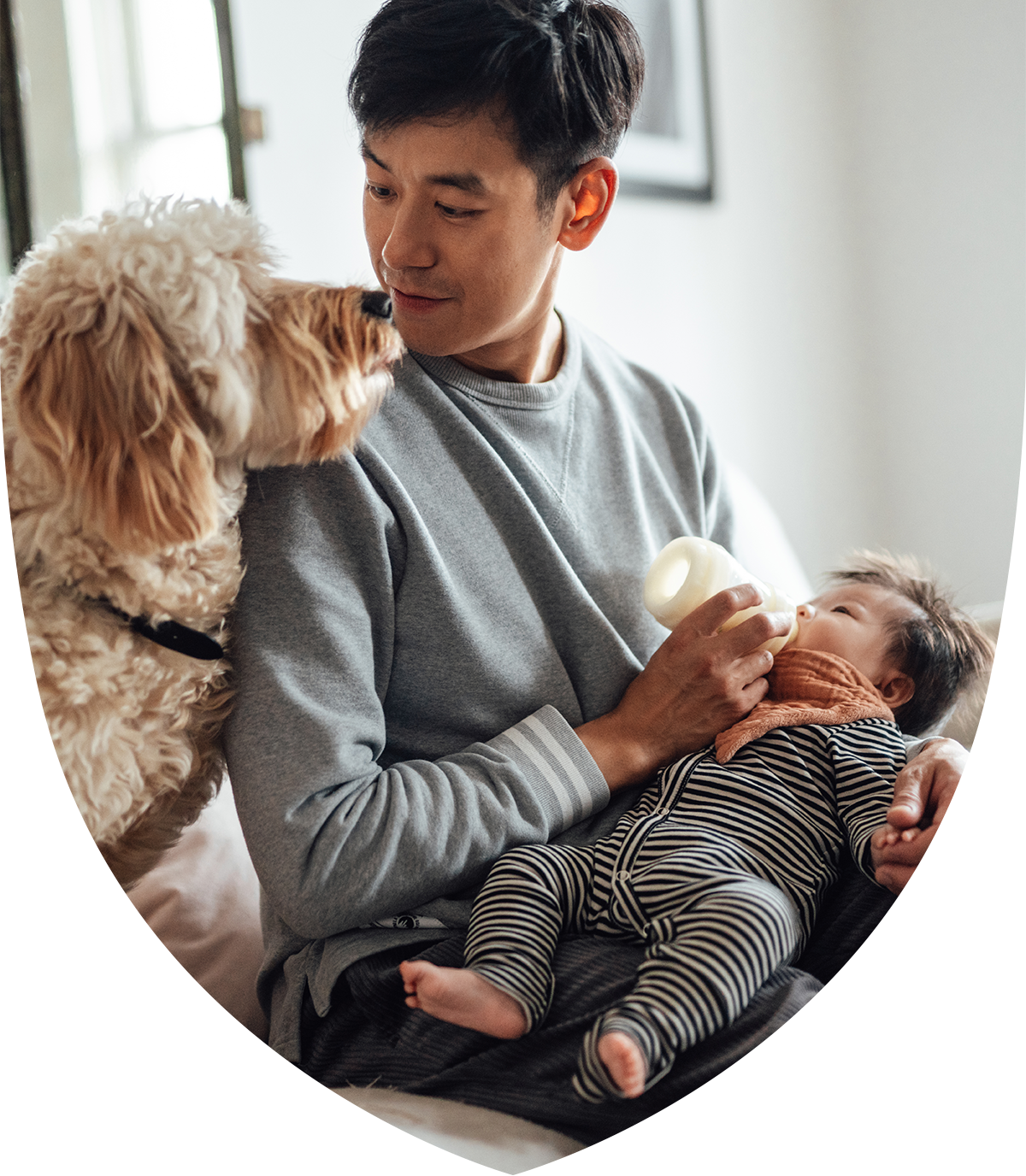 A man holding a baby and a dog over his shoulder
