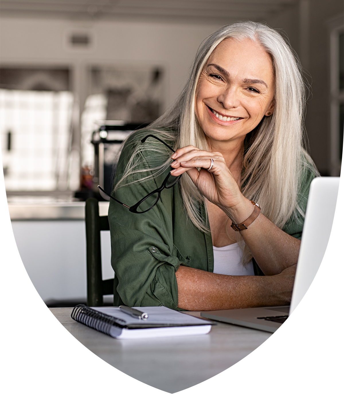 Close up of a woman holding her glasses and sitting at a laptop