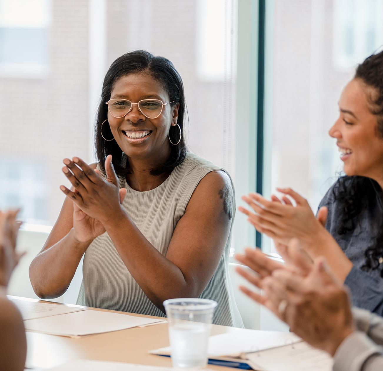 Diverse female financial professionals smiling and clapping together