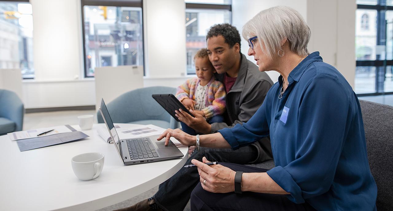 A financial advisor helping a client and his son on the computer