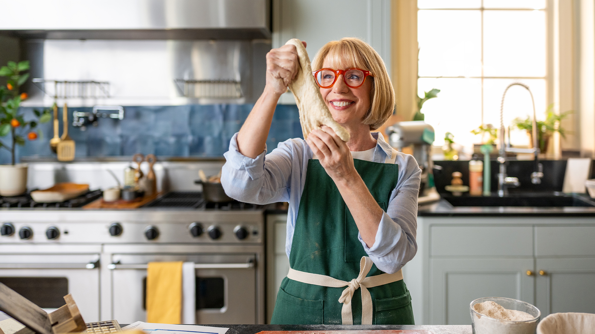 Elderly woman stretching out dough in her kitchen