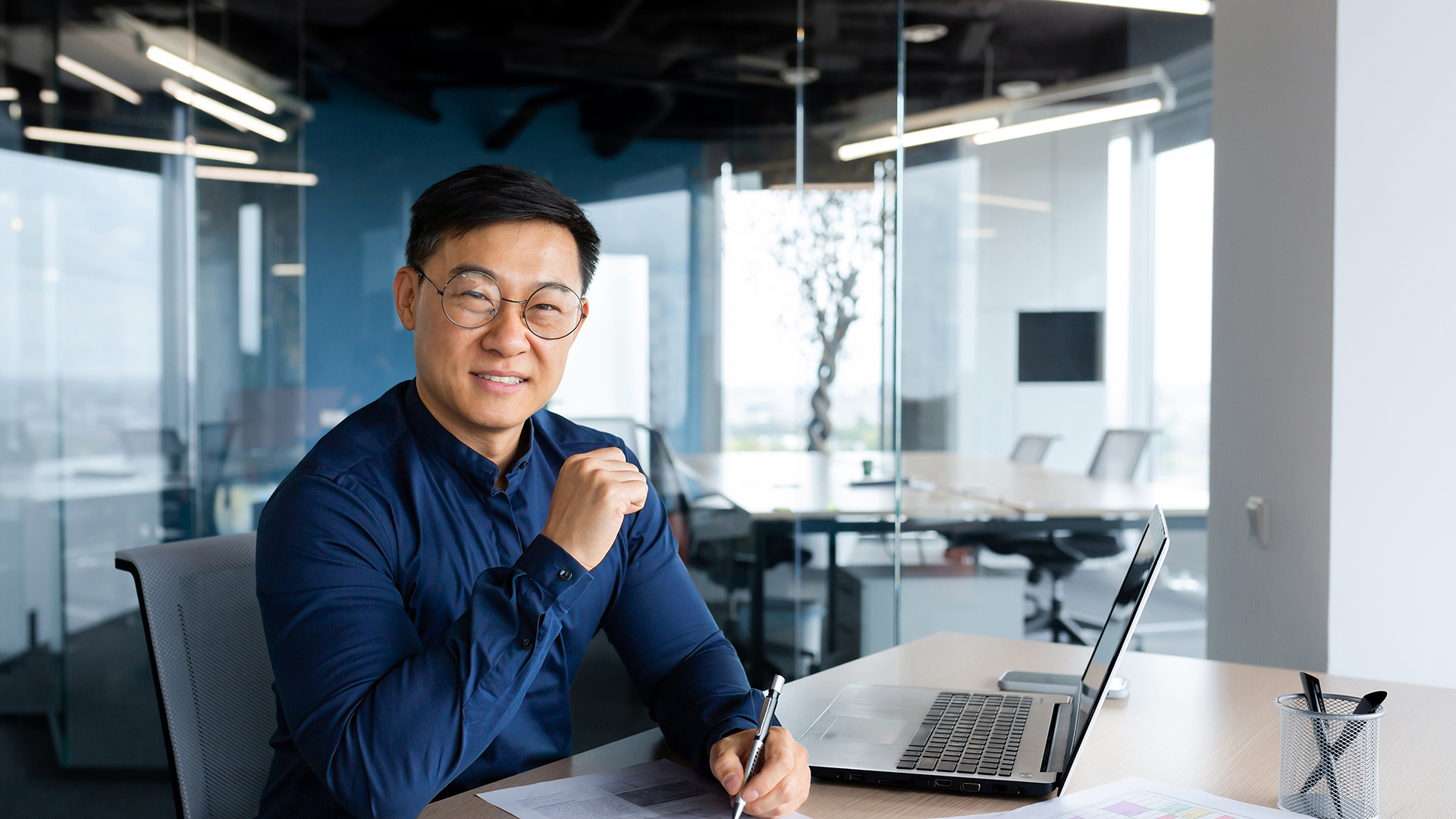 Middle aged man in blue button down sitting at his desk