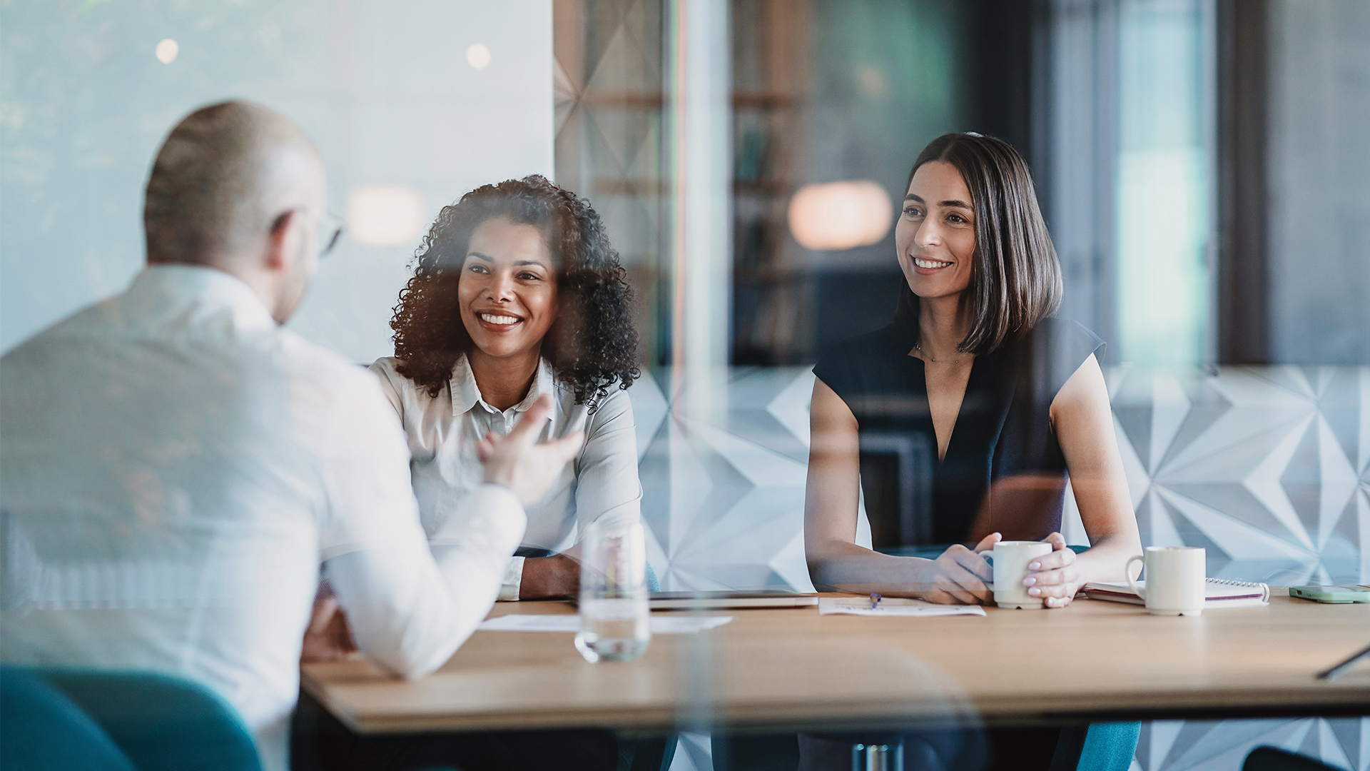 Two women speaking with another man in the office