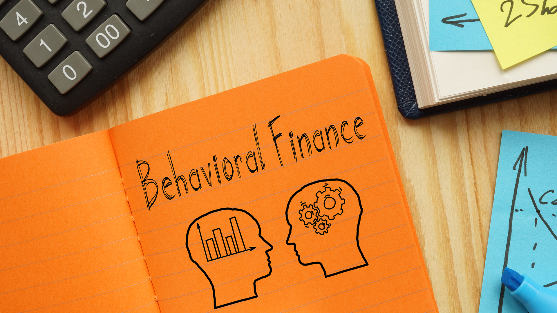 "Behavioral Finance" written on an orange notepad
