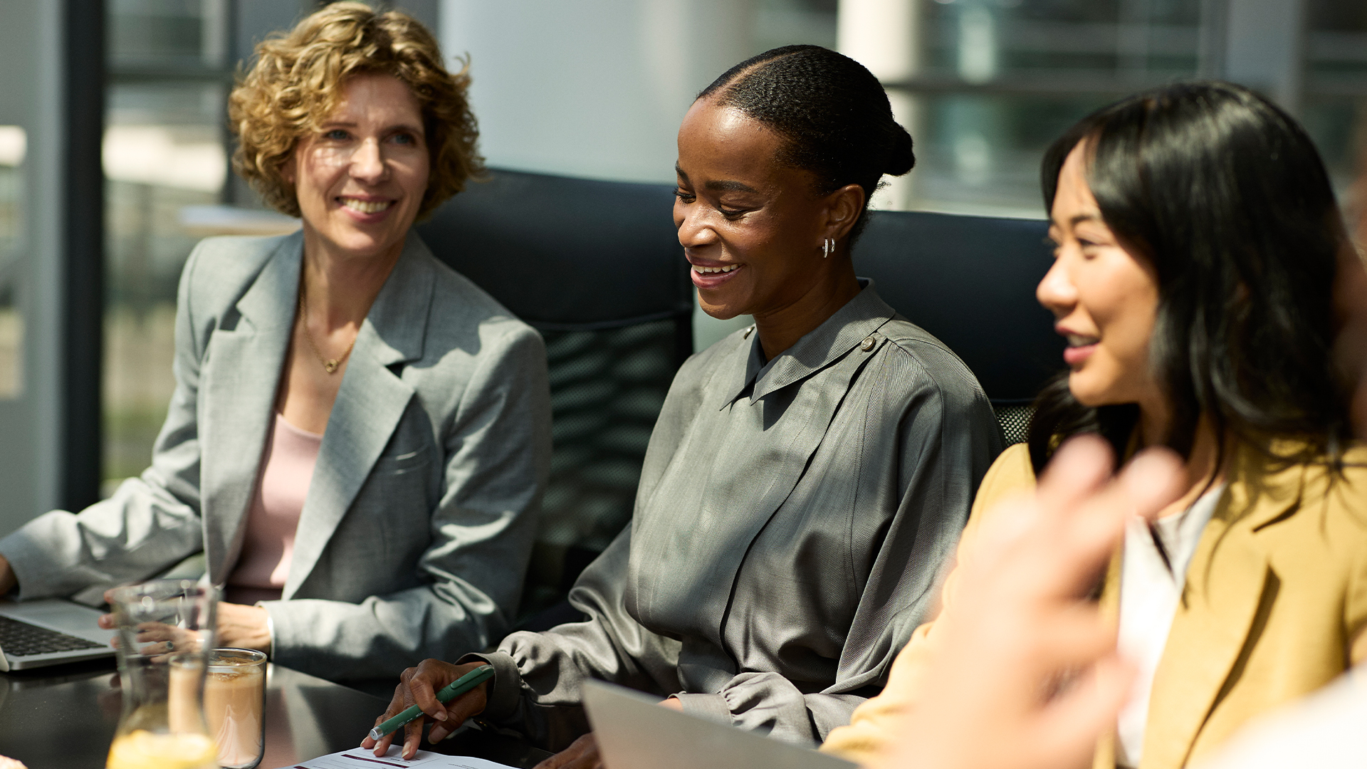 Three professional females sitting at a conference table in a meeting