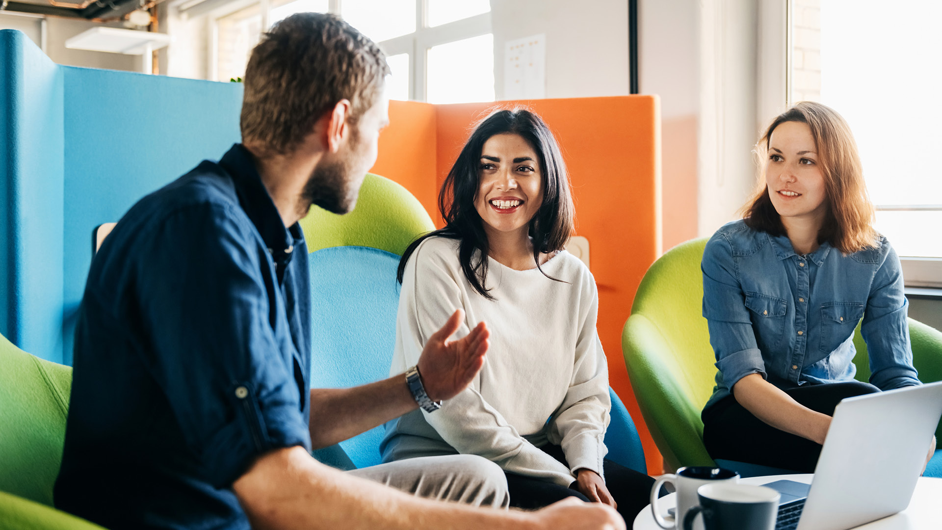 Two women and a man talking in the office