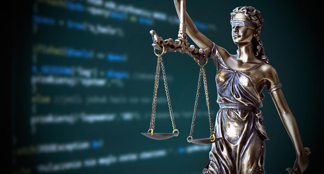 Statue of judge with scales in front of computer screen of code