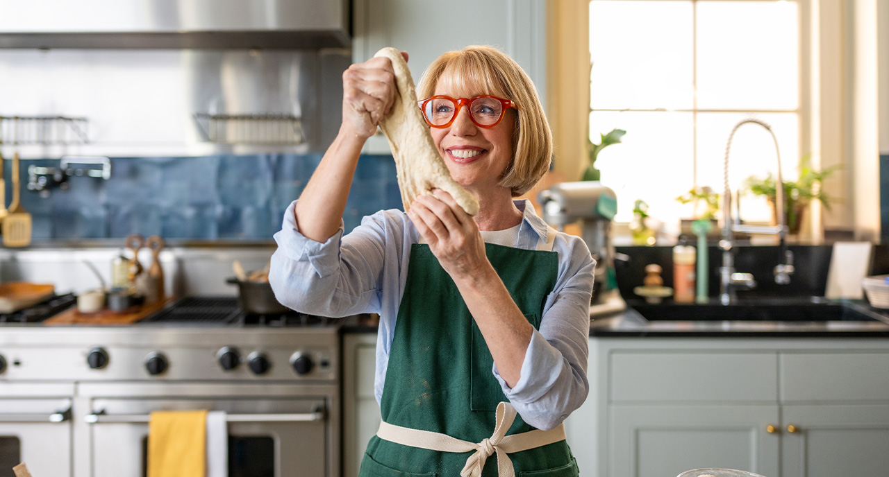 Elderly woman stretching out dough in her kitchen