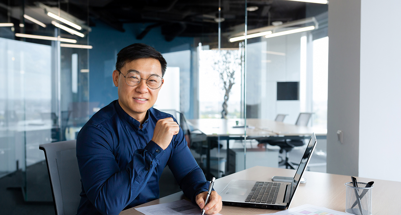 Middle aged man in blue button down sitting at his desk
