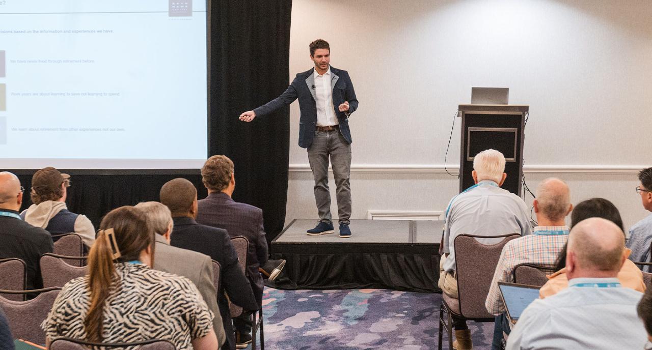 Jamie Hopkins speaking on stage at an event