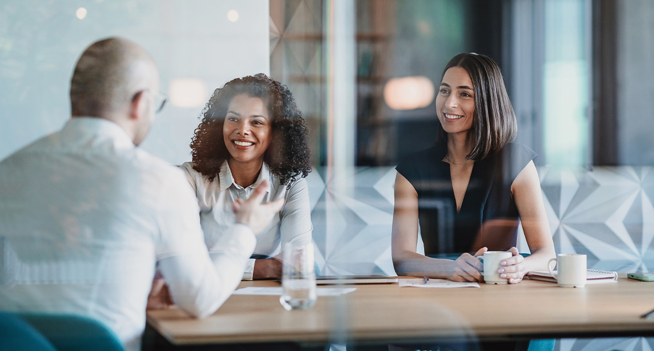 Two women speaking with another man in the office