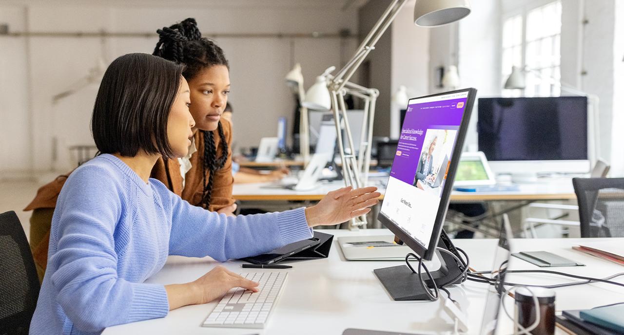 Two female coworkers looking at a computer together