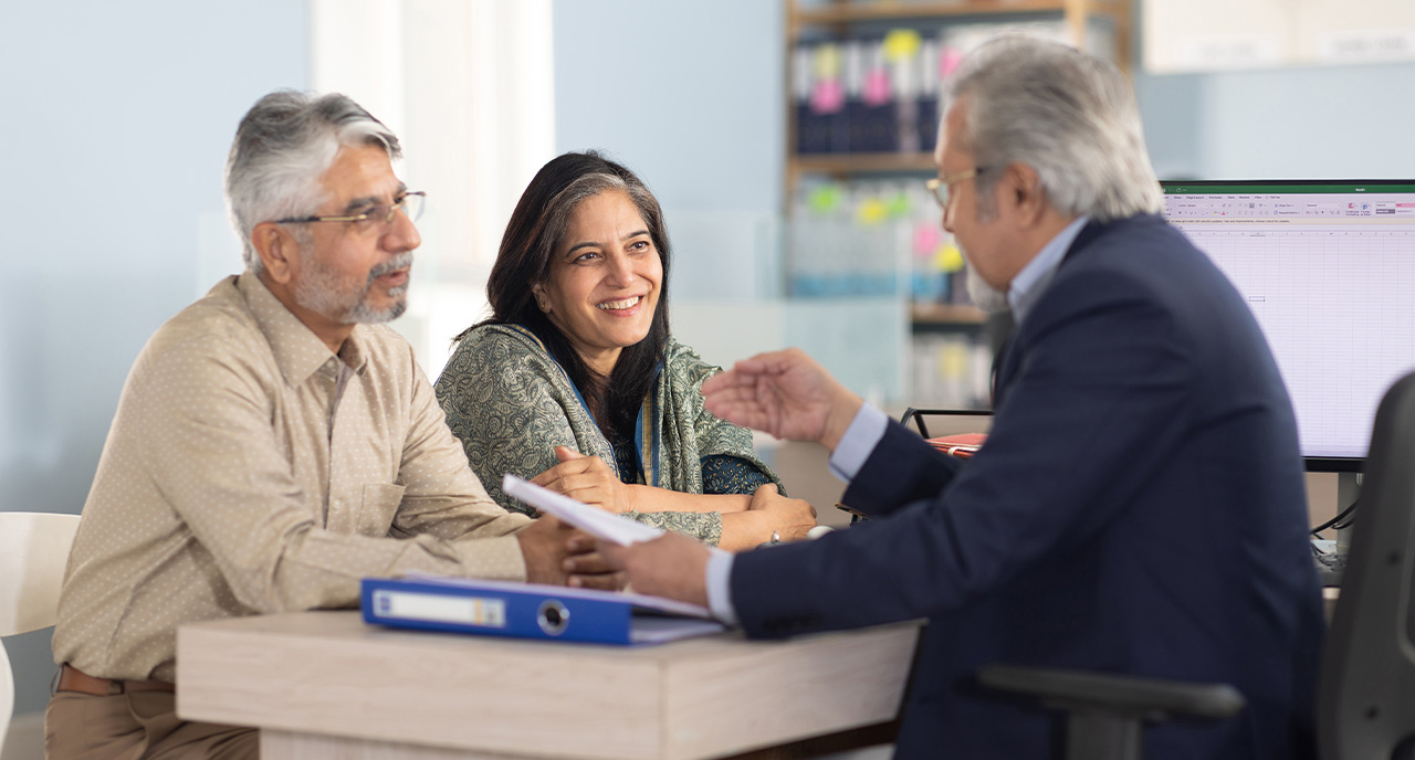 Middle aged male advisor meeting with his retiree couple clients