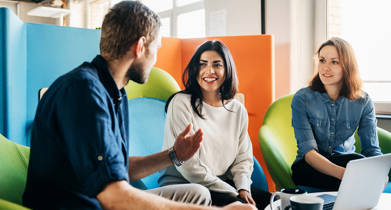 Two women and a man talking in the office