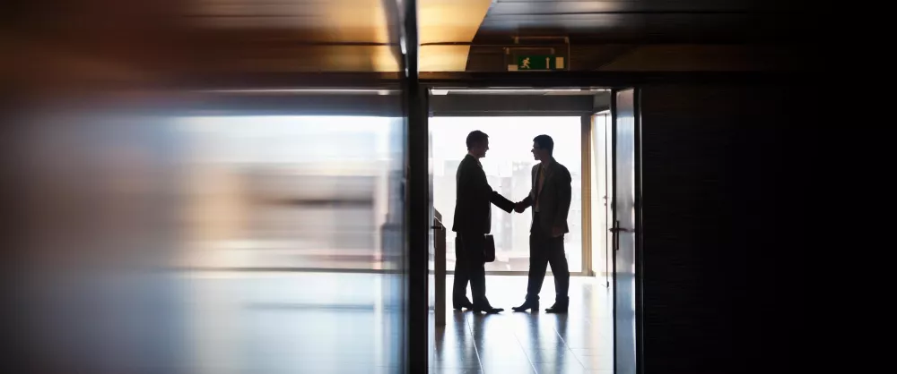 Two people shaking hands down a hallway