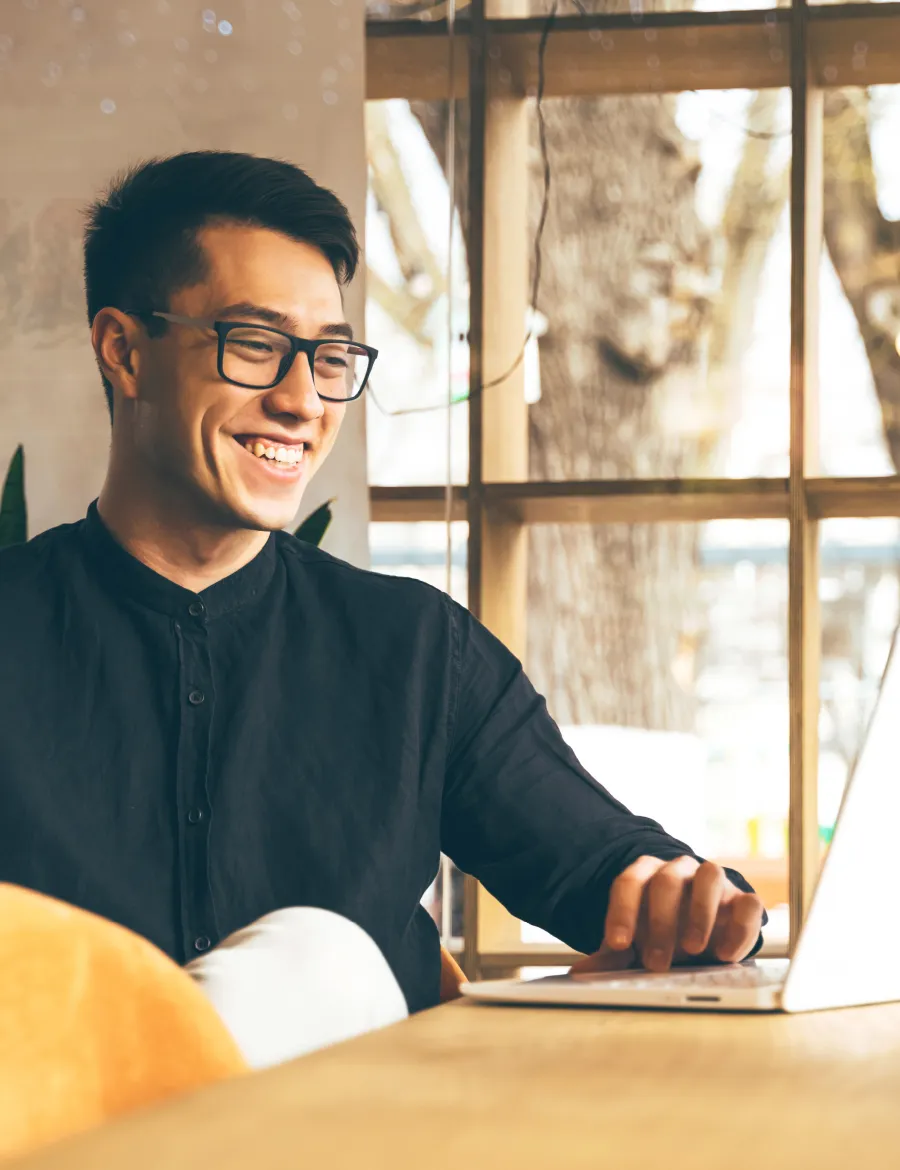 Asian male in his 30's smiling at his desk