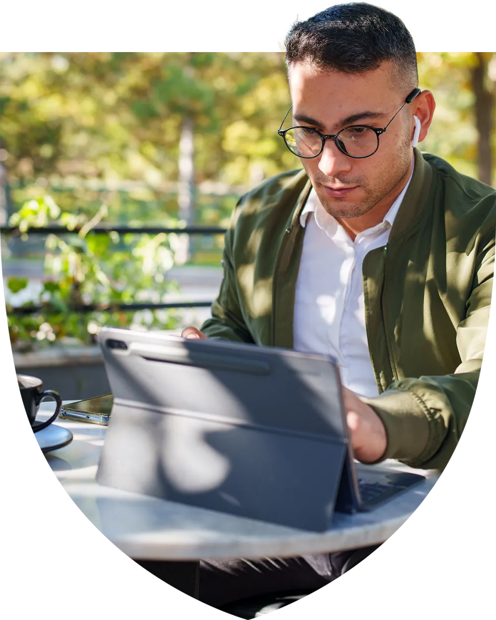Man with glasses sitting outside at a cafe working on his laptop