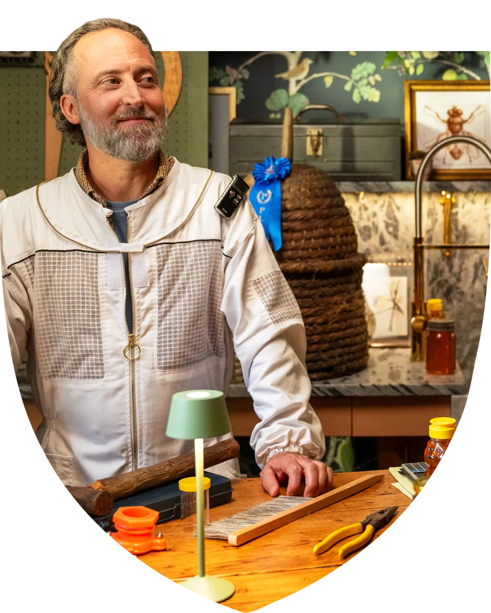 Man in beekeeper suit standing proudly at his desk