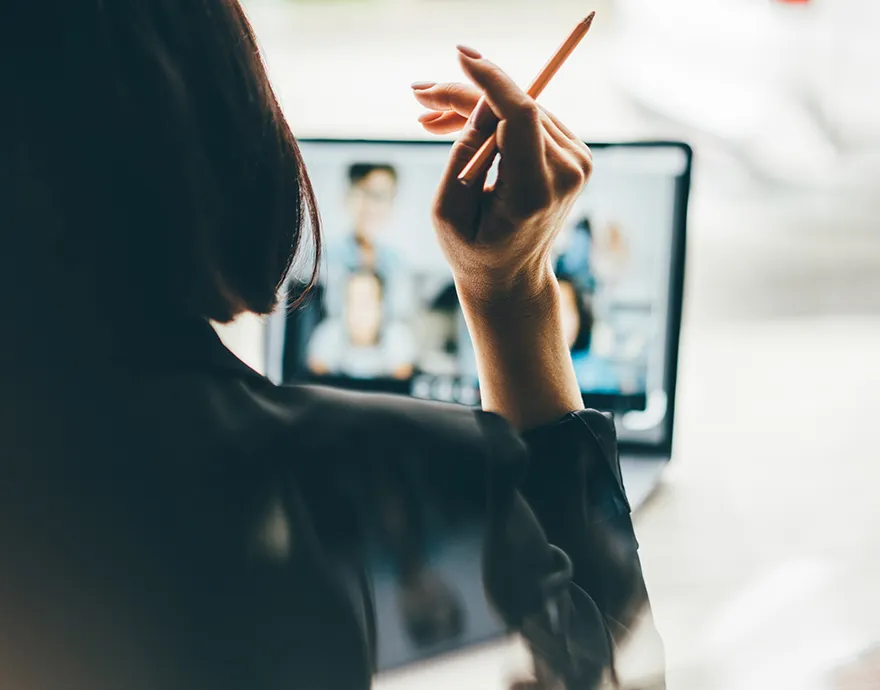 Woman holding a pen while on a virtual meeting