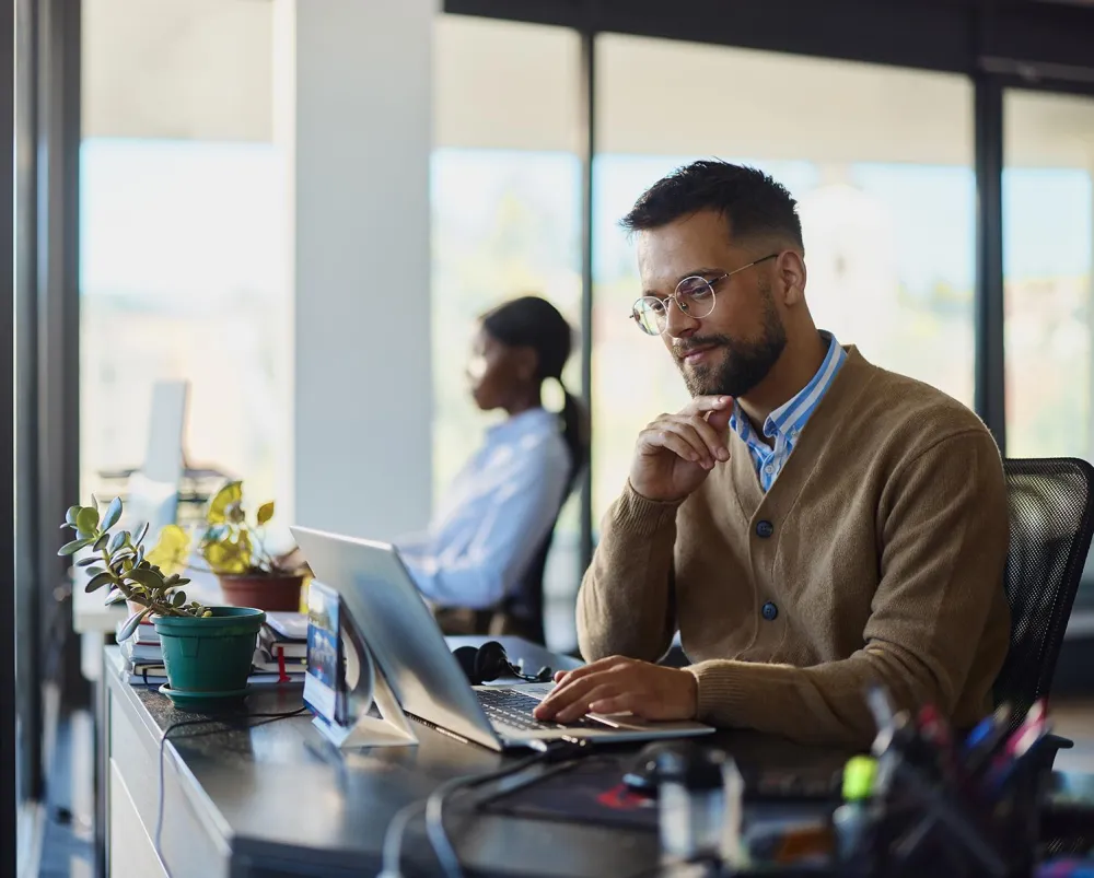 Young financial professional smiling while working at his desk