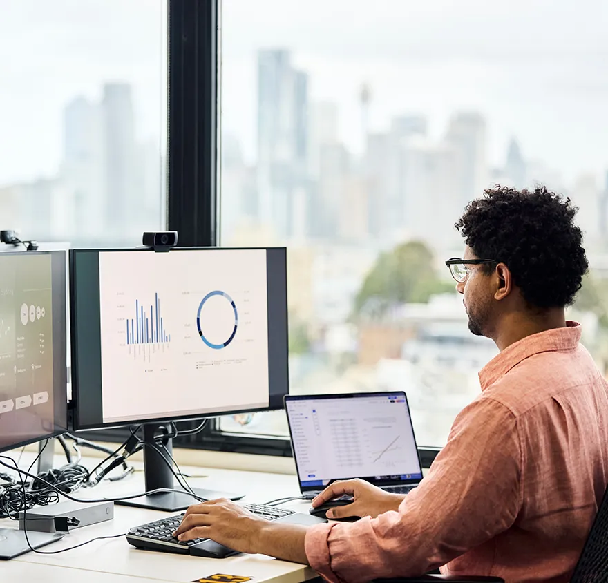 Man sitting at his desk reviewing data sheets with city skyline outside