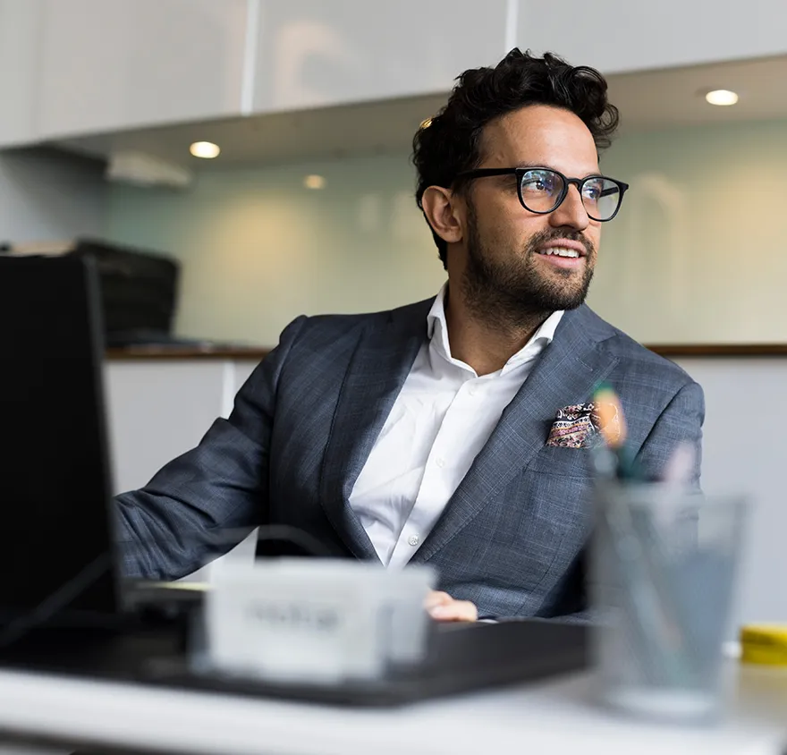 Professional male in his 30's sitting at his desk at work