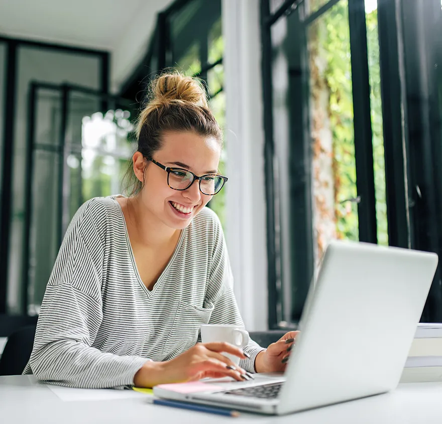 Woman in her 30's sitting at her laptop and smiling