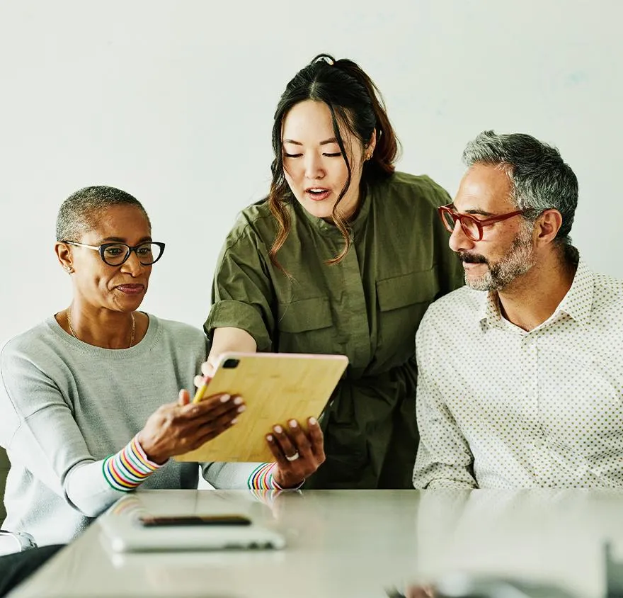 Three coworkers looking at notes on a tablet