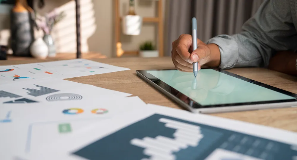 Woman sitting at a table and writing on their tablet