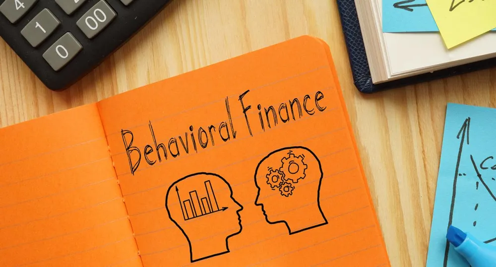 "Behavioral Finance" written on an orange notepad