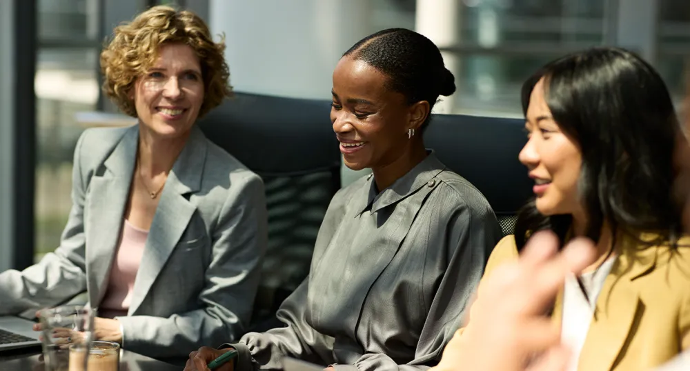 Three professional females sitting at a conference table in a meeting