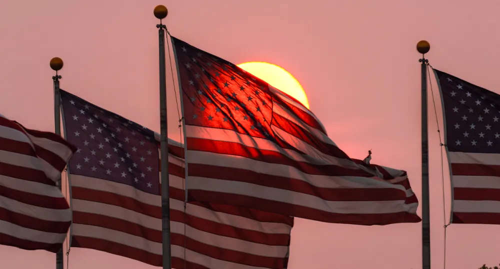 Four American Flags waving in the sunset