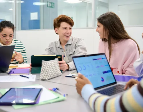 A female professor sitting with a group of students at the table