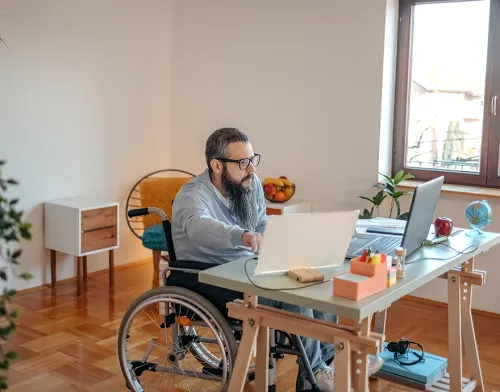 Man in wheelchair working at his desk in the office