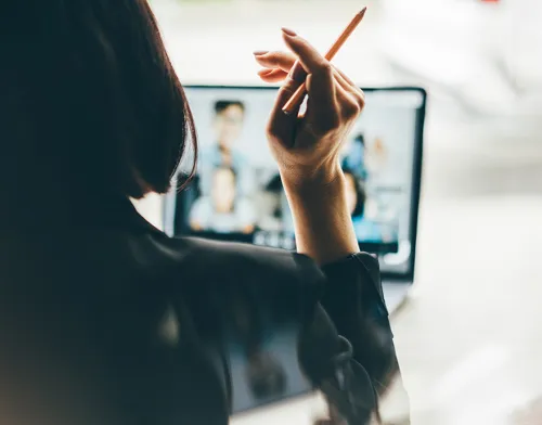 Woman holding a pen while on a virtual meeting