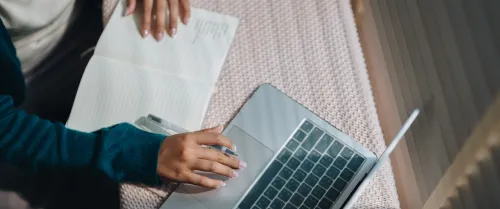 Woman using her laptop and looking at notes
