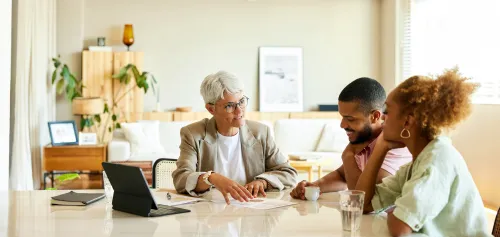 Senior financial advisor helping her younger clients at the table