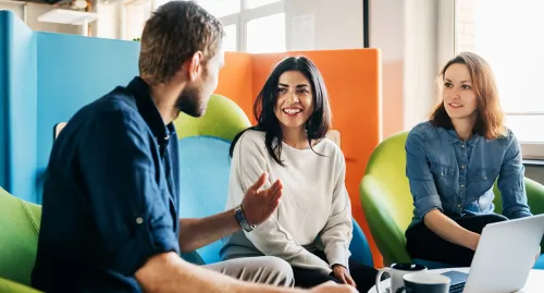 Two women and a man talking in the office