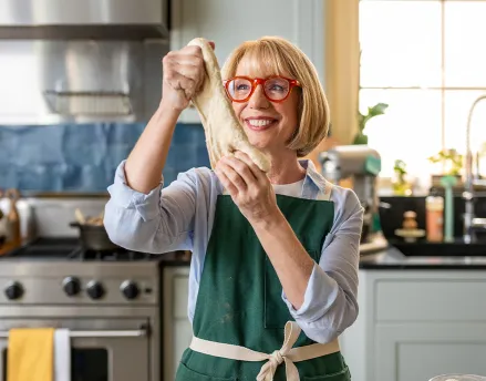 Elderly woman stretching out dough in her kitchen